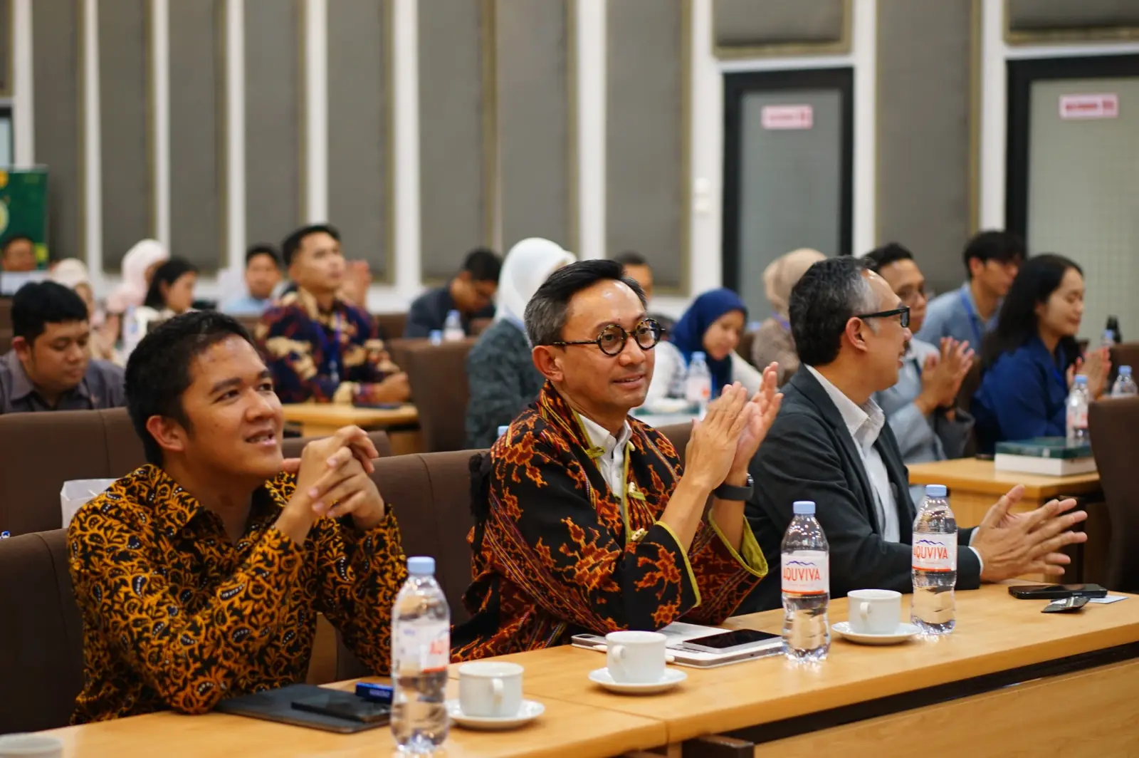 Communication leaders applauding in the audience at a forum session